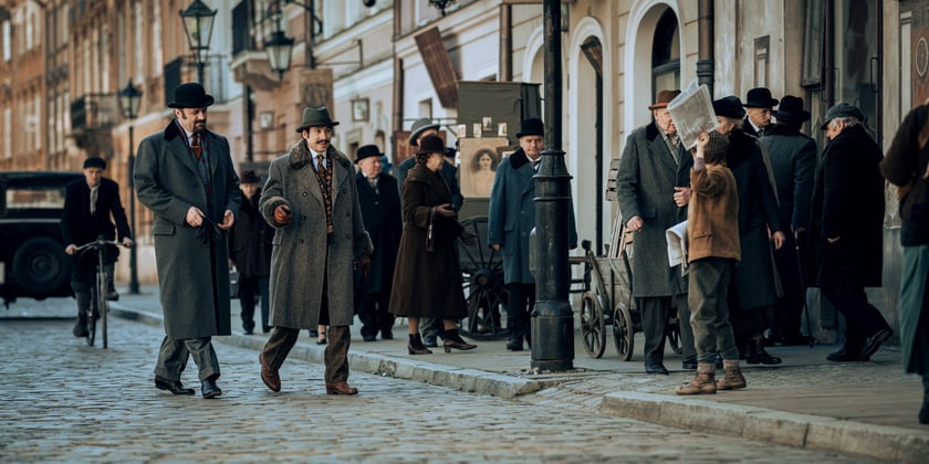 Kadr z filmu "Znachor" Netflixu. Na zdjęciu od lewej Leszek Lichota, Mirosław Haniszewski, w tle grupa statystów