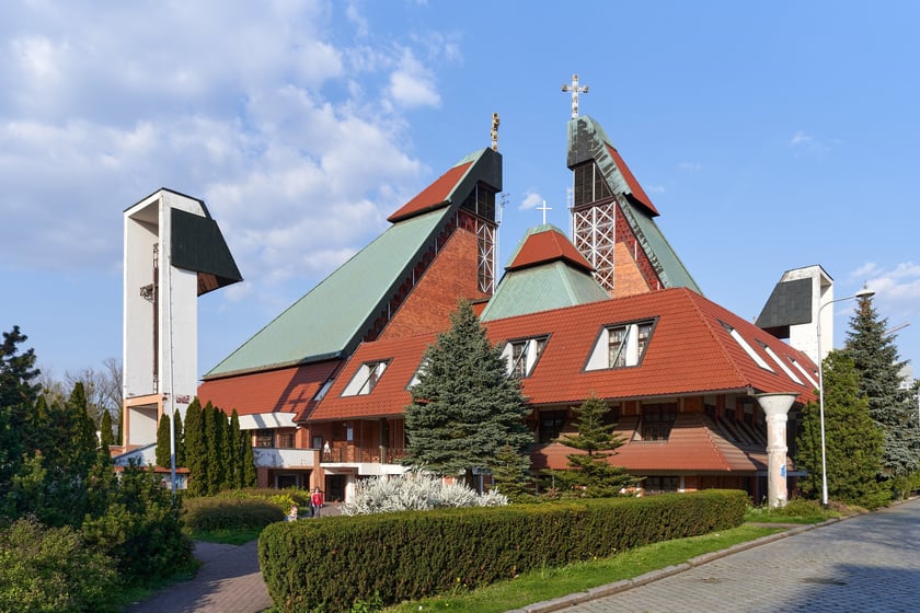 Kości&oacute;ł pw. Chrystusa Kr&oacute;la budowany był w latach 1978-1991 na planie kwadratu. Budowla przypomina ostrosłup złożony z czterech części, podobnych do wież, o zr&oacute;żnicowanej wysokości. Zbiegające się &nbsp;ku środkowi ściany owych wież przykrywają centralną (sakralną) część budowli, nadając jej ekspresyjny charakter. Nachylone połacie zdobi dekoracja przypominająca strukturę kryształu. W przyziemiu mieści się kaplica św. Mikołaja, ośrodek kultury i szkoła.