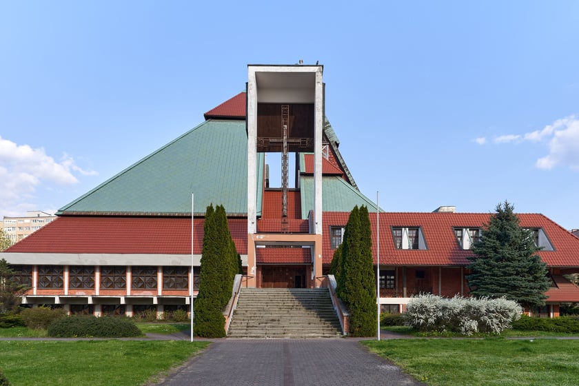 Kości&oacute;ł pw. Chrystusa Kr&oacute;la budowany był w latach 1978-1991 na planie kwadratu. Budowla przypomina ostrosłup złożony z czterech części, podobnych do wież, o zr&oacute;żnicowanej wysokości. Zbiegające się &nbsp;ku środkowi ściany owych wież przykrywają centralną (sakralną) część budowli, nadając jej ekspresyjny charakter. Nachylone połacie zdobi dekoracja przypominająca strukturę kryształu. W przyziemiu mieści się kaplica św. Mikołaja, ośrodek kultury i szkoła.