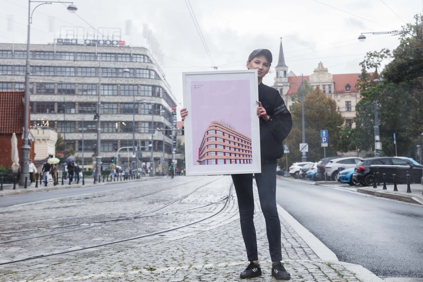 Malwa Domaradzka z plakatem, na kt&oacute;rym przedstawiła Renomę na tle prawdziwego budynku