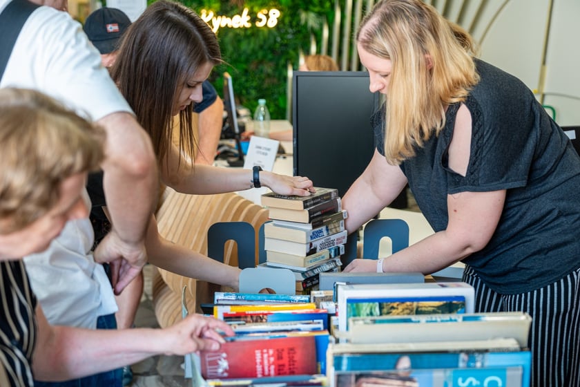 Czytelnicy przeglądający książki i inne zbiory wystawione na sprzedaż w Dolnośląskiej Bibliotece Publicznej w rynku