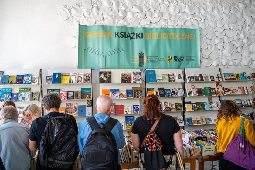 Czytelnicy przeglądający książki i inne zbiory wystawione na sprzedaż w Dolnośląskiej Bibliotece Publicznej w rynku