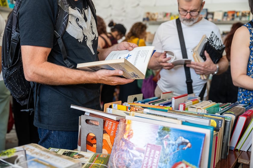 Czytelnicy przeglądający książki i inne zbiory wystawione na sprzedaż w Dolnośląskiej Bibliotece Publicznej w rynku