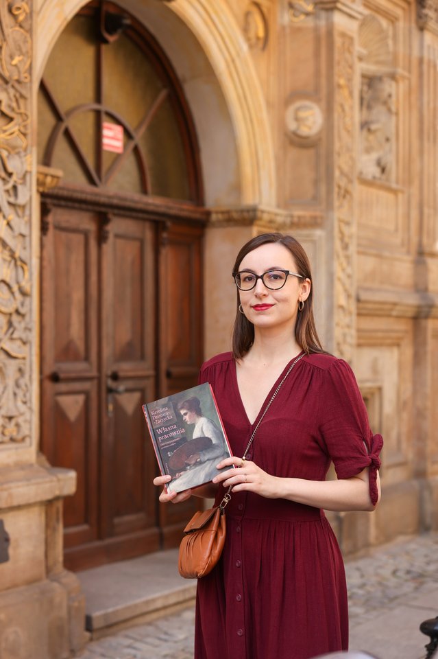 Na zdjęciu Karolina Dzimira-Zarzycka z książką &bdquo;Własna pracownia&rdquo; przy kamienicy, w kt&oacute;rej mieszkała wrocławska malarka Hanna Krzetucka-Geppert