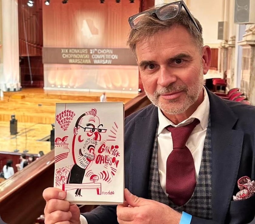 <p>Tomasz Broda z karykaturą przewodniczącego jury Konkursu Chopinowskiego Garricka Ohlsssona</p>