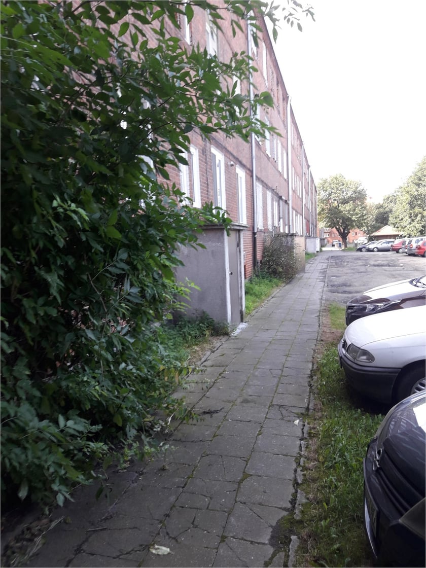 Podwórko przy Hallera przed rewitalizacją - widok na chodnik ze starych betonowych płyt