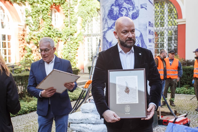 Pamiątkowy papier czerpany z wyciętego kasztanowca, otrzymał go stojący na pierwszym planie zdjęcia Jacek Sutryk. prezydent Wrocławia