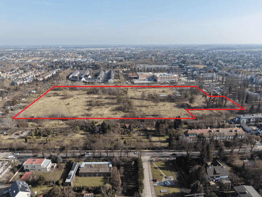 Widok z lotu ptaka na budynki, drzewa i tereny zielone - obszar między ulicami Ołtaszyńską i Zwycięską, który Wrocław ma otrzymać od AMW (oznaczony czerwona linią).