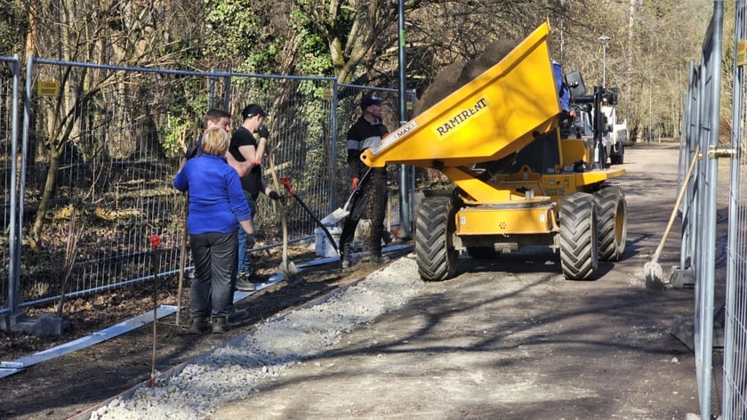 Robotnicy i maszyna budowlana wioząca ziemię na Alei Romera w Parku Grabiszyńskim.