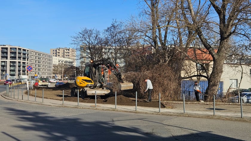 Koparka i pracownicy pracujący na terenie przy chodniku na ul. Ziębickiej