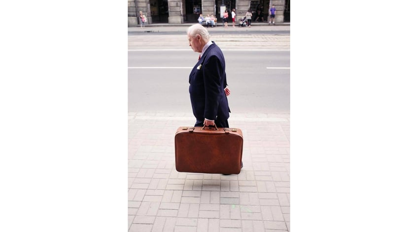 Na zdjęciu postać z walizką. Fotografia Jacka Szusta, która znalazła się w książce Davida Gibsona pod tytułem „100 Great Street Photographs”.