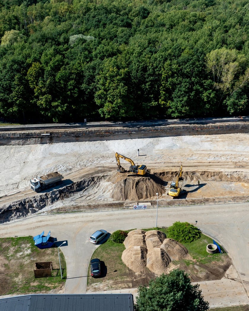 Widok wykopu z ciężarówkami i koparkami lotu ptaka. Budowa zbiornika wody w zakładzie "Mokry Dwór".