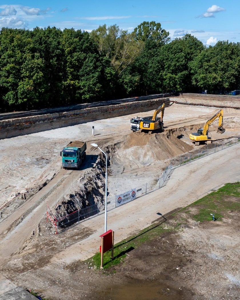 Widok wykopu z ciężarówkami i koparkami lotu ptaka. Budowa zbiornika wody w zakładzie "Mokry Dwór".