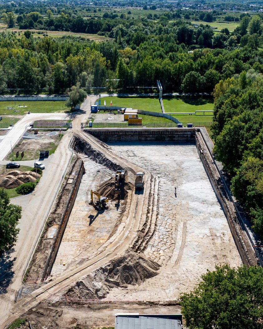 Widok wykopu z ciężarówkami i koparkami lotu ptaka. Budowa zbiornika wody w zakładzie "Mokry Dwór".
