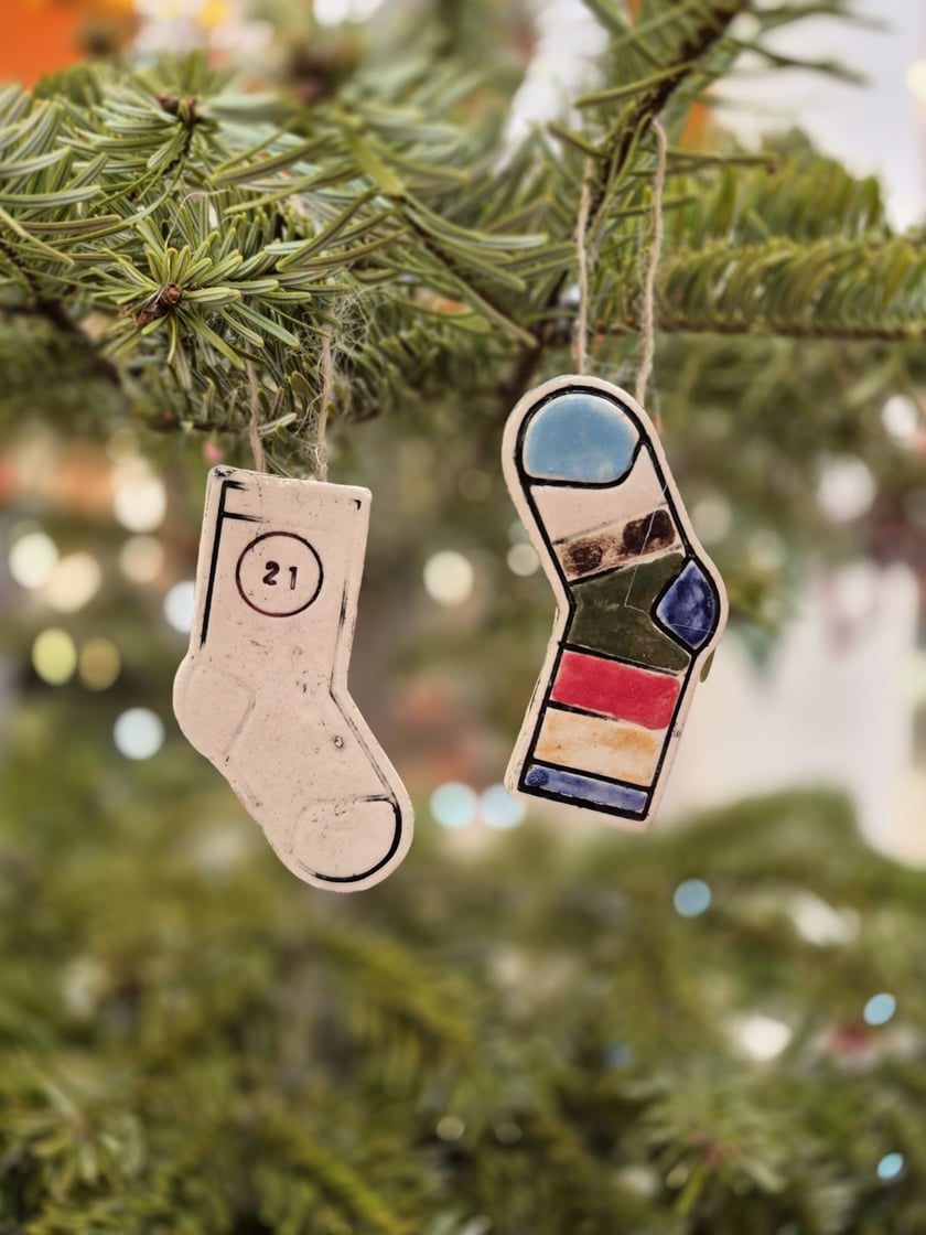 Powiększ obraz: <p>Kiermasz świąteczny Fundacji Kolorowe Skarpetki w Alei Bielany. Na zdjęciu dwie ozdoby choinkowe w kształcie skarpetek.</p>