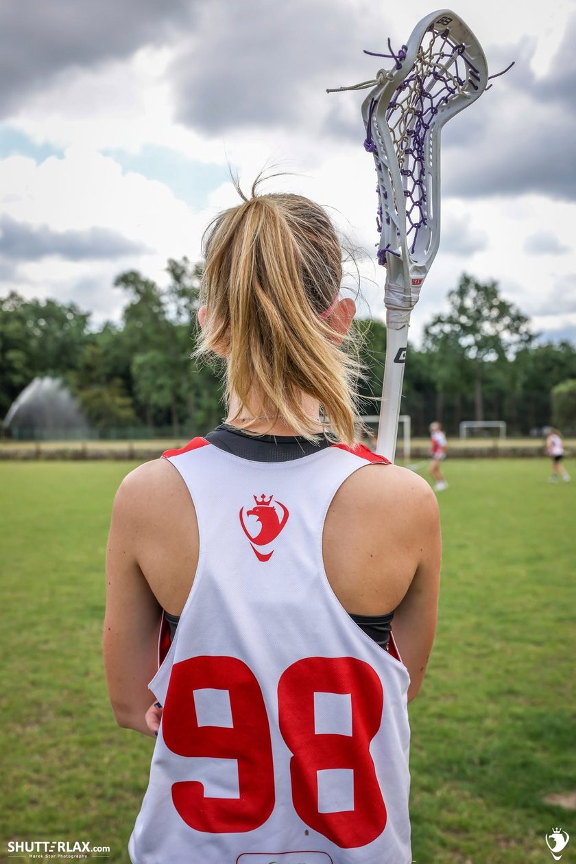 Powiększ obraz: Zawodniczka lacrosse stoi plecami do zdjęcia