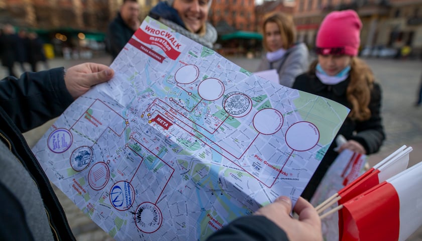 Na zdjęciu uczestnik WrocWalk Marathon 2021 ogląda mapę z miejscami na pieczątki w punktach kontrolnych