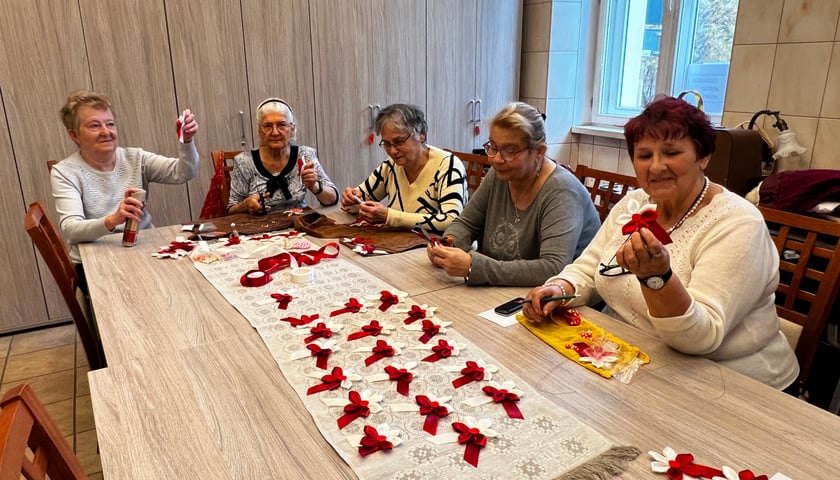 Na zdjęciu grupa seniorek w czasie przygotowywania kotylionów na Święto Niepodległości