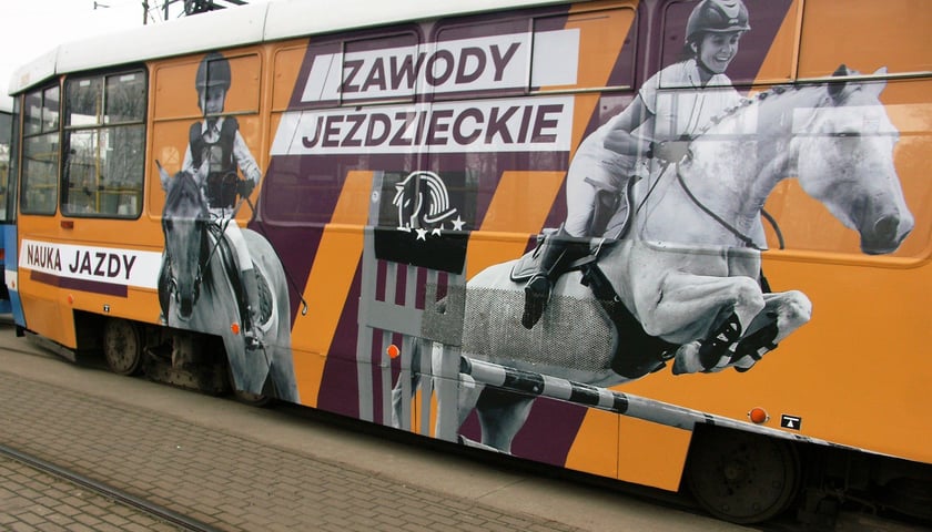 Na zdjęciu: wagon tramwajowy z grafiką pokazującą dwójkę jeźdźców - dziecko i kobietę - na koniach