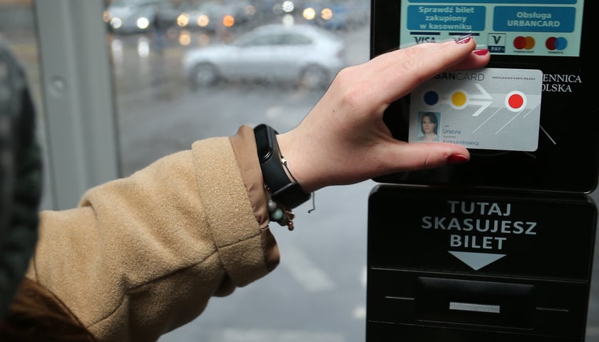 Osoba przykładająca URBANCARD do kasownika w pojeździe MPK
