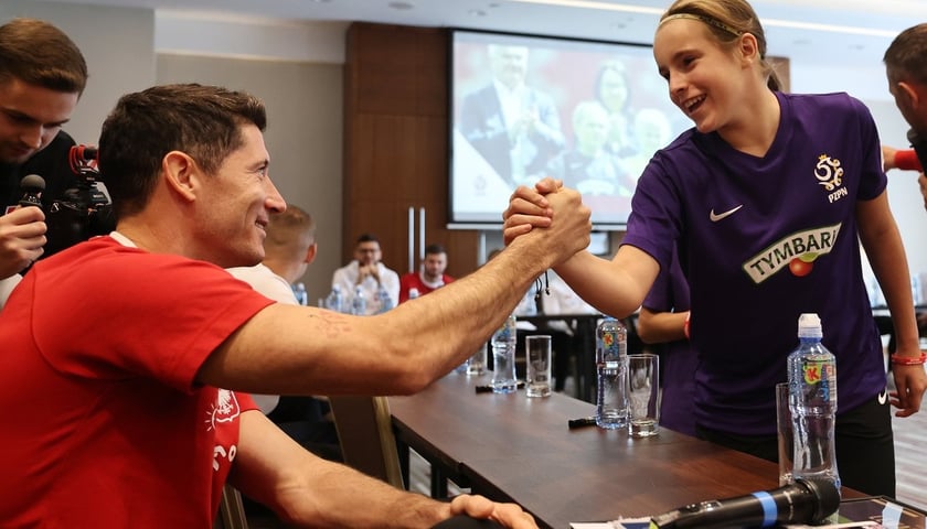 Na zdjęciu widać Roberta Lewandowskiego i dziewczynkę grającą w piłkę nożną 