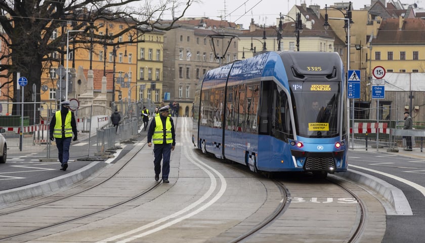 Na zdjęciu: torowisko, dwaj mężczyźni w żółtych kamizelkach i tramwaj na moście Pomorskim 