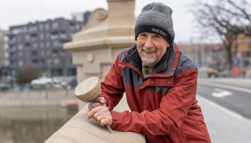 Na zdjęciu: uśmiechnięty Kazimierz Durawa, opierający się o balustradę mostu Pomorskiego Południowego, z narzędziem i przedmiotem z kamienia w dłoniach 