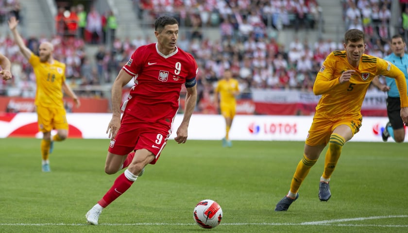 Na zdjęciu: Robert Lewandowski (czerwony strój) wpada z piłką w pole karne Walijczyków 