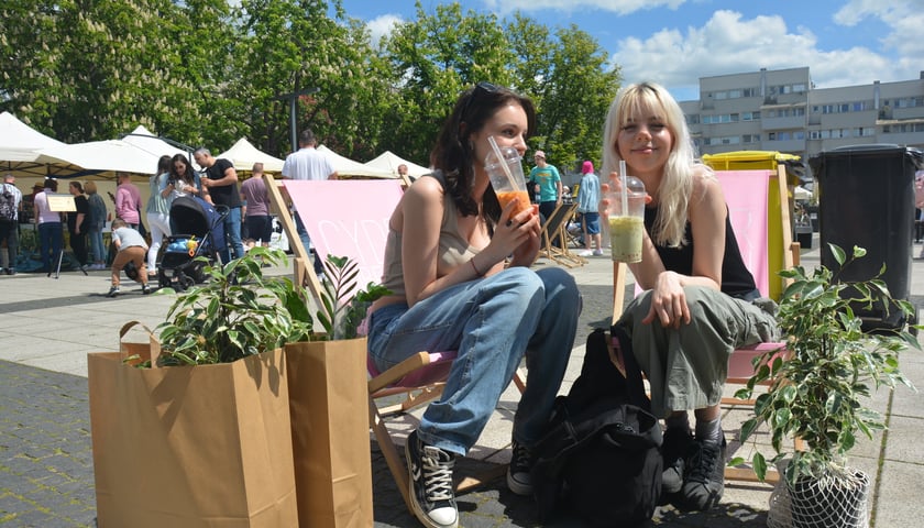 Brunetka i blondynka z napojami na leżakach na placu Nowy Targ