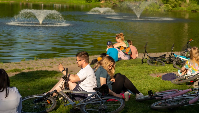 Grupki ludzi siedzących na trawie w Parku Południowym, obok nich leżą rowery (zdjęcie ilustracyjne)     