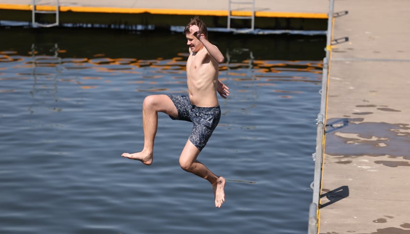 Ludzie na kąpielisku Morskie Oko. Na zdjęciu młody mężczyzna wskakuje do wody