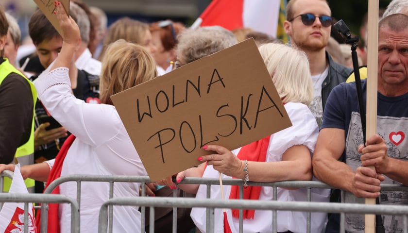 Wiec Donalda Tuska na Nowym Targu. Uczestnicy z flagami, na pierwszym planie transparent z hasłem "Wolna Polska"
