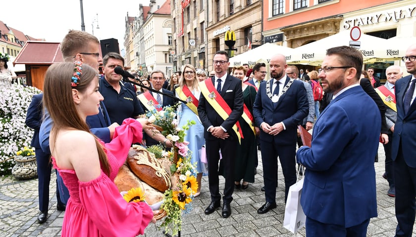Jacek Sutryk (prezydent) i Sergiusz Kmiecik (przewodniczący rady miejskiej) odbierają bukiet kwiatów na rynku podczas Święta Wrocławia