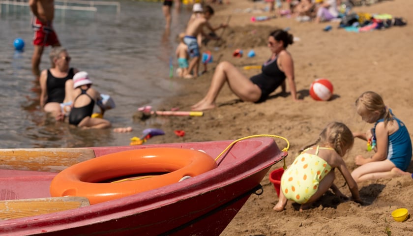 Kąpielisko Glinianki we Wrocławiu. Na zdjeciu widać małe dzieci bawiące się na brzegu oraz dorosłych opalających się nad wodą