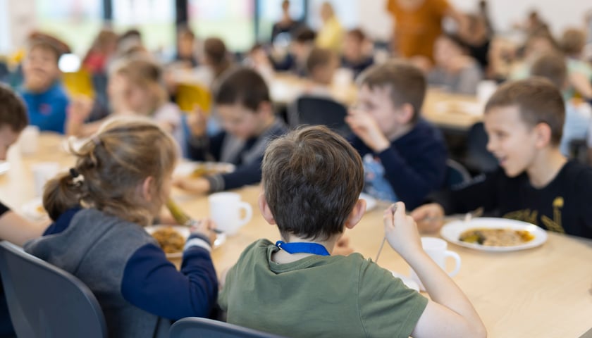 Dzieci siedzące przy stolikach w szkolnej stołówce