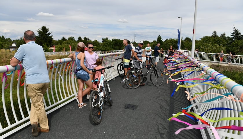 Otwarcie kładki nad Ślęzą. Na zdjęciu widać pieszych i rowerzystów na nowej kładce ustrojonej kolorowymi wstążkami