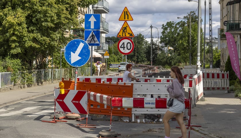 Dwie kobiety (w tle trzecia) koło znaków drogowych i biało-czerwonych osłon remontowych na ulicy Dolnobrzeskiej w Leśnicy