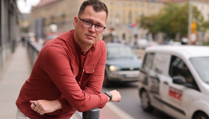 Mateusz Rydlewski oparty o słupek, w centrum Wrocławia