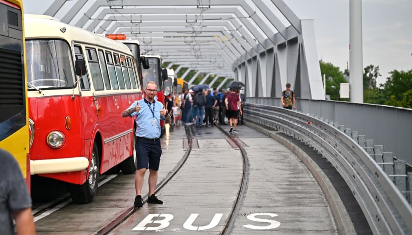 Inauguracją połączeń autobusowych przez nowy wiadukt na trasie na Nowy Dwór była 21 lipca parada starych autobusów. Na zdjęciu czerwono-kremowy autobus marki Jelcz, kierowca, a w tle dużo ludzi biorących udział w paradzie. 