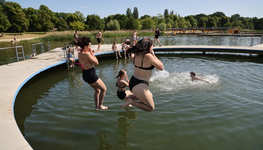 Na zdjęciu grupa młodych ludzi wskakuje do wody. Kąpielisko Morskie Oko