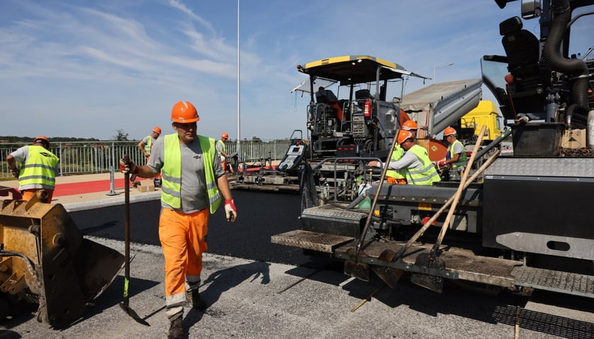 Robotnicy pracujący na wiadukcie, układają ostatnią warstwę nawierzchni 