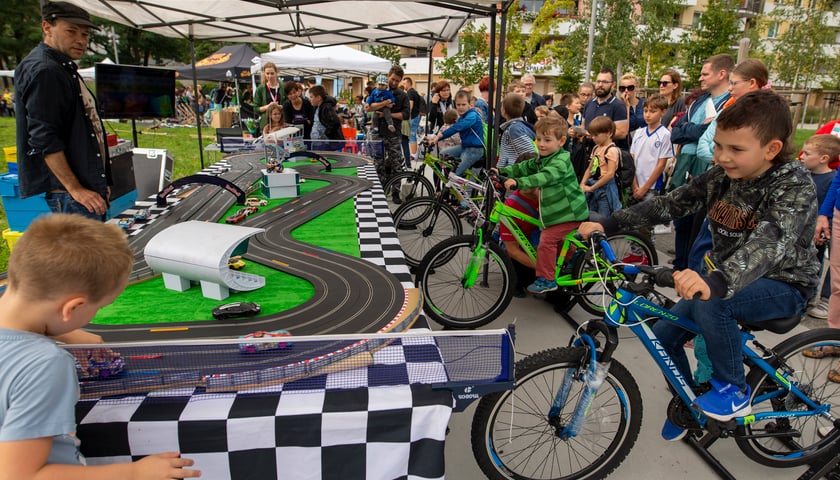 Dzieci na rowerach, które napędzały energią nóg samochodziki na torze wyścigowym podczas pikniku w 2021 roku