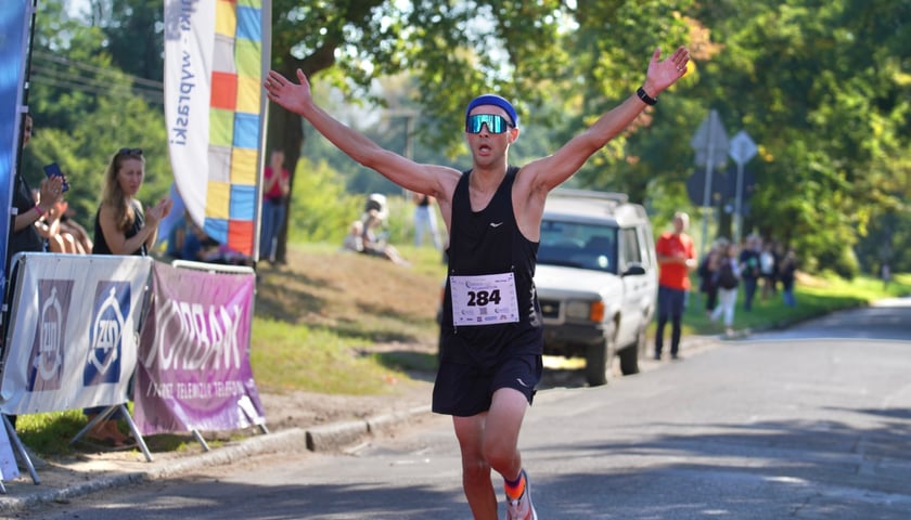Paweł Gaczew, zwycięzca półmaratonu H2O, wbiega na metę z rozłożonymi nad głową rękami