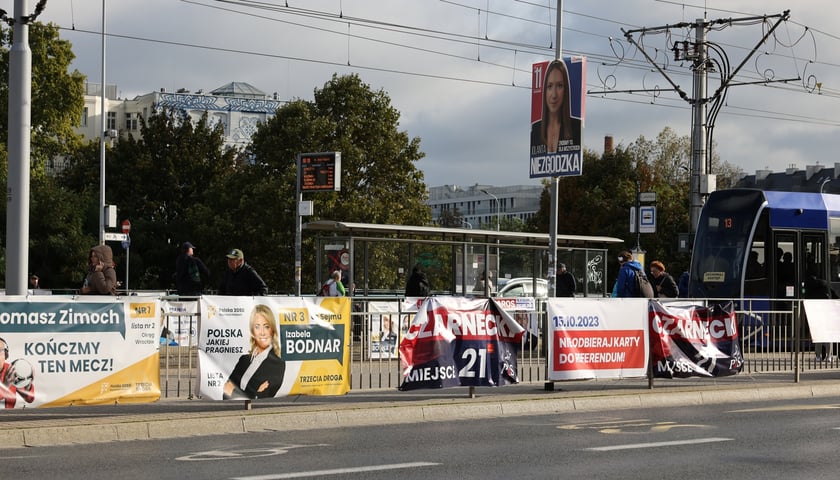 Plakaty wyborcze na ogrodzeniu przystanku