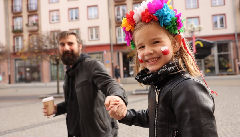 Uśmiechnięta dziewczynka z wiankiem trzymająca za rękę mężczyznę podczas WrocWalk 2023