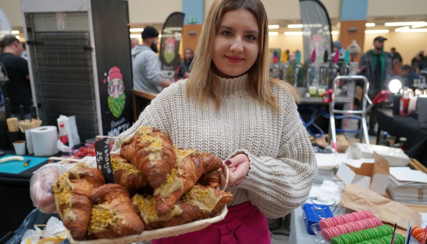 Młoda kobieta na jednym ze stoisk festiwalu kulinarnego w Hali IASE z rogalami.