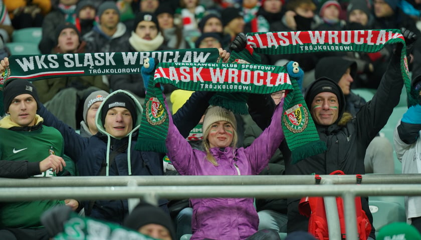 Mecz Śląsk Wrocław kontra Raków Częstochowa. Na zdjęciu kibice, którzy siedzą na trybunach i trzymają w rękach szaliki WKS-u