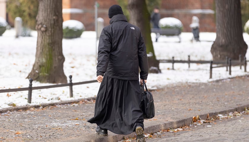 Ksiądz w sutannie idący ulicą