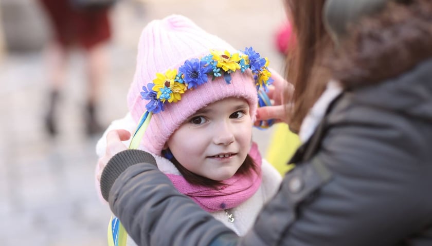 Dziewczynka w różowej czapce i wianuszku z niebieskich i żółtych kwiatów. Uroczystości związane z drugą rocznicą wybuchu wojny w Ukrainie (24 lutego 2024)