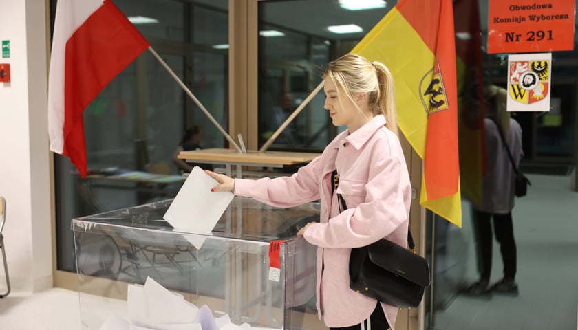Młoda blondynka wrzucająca kartę do urny w lokalu na Jagodnie, 7 kwietnia 2024 roku
